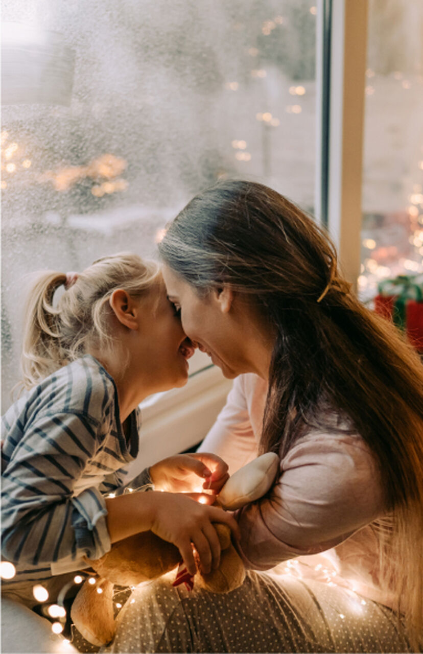 A little girl and her mother playing together, both smiling happily.